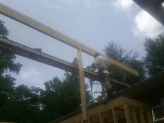 Carpenter setting a ridge beam over a new addition frame — Ice Dam Removal by Roofing Brothers in Big Sandy