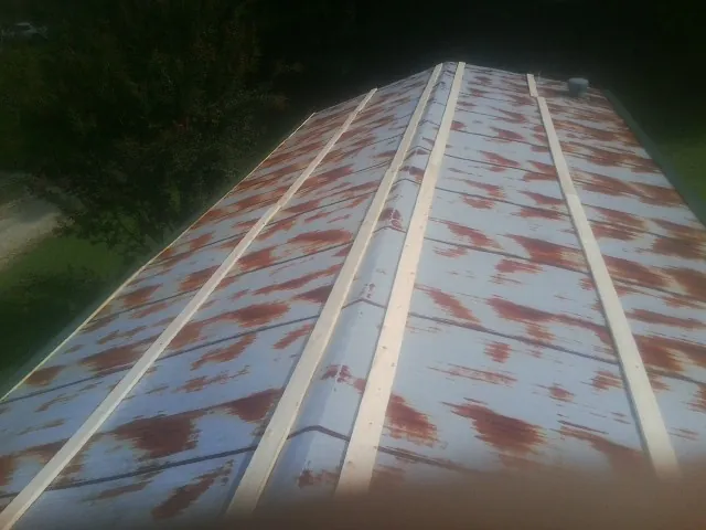 Rusted metal roof panels with new wood purlins before replacement — Storm Damage Roof Repair in Big Sandy by Roofing Brothers