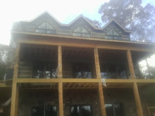 Dormers and porch framing on a large log home under construction — Roof Coating work by our crew in Big Sandy