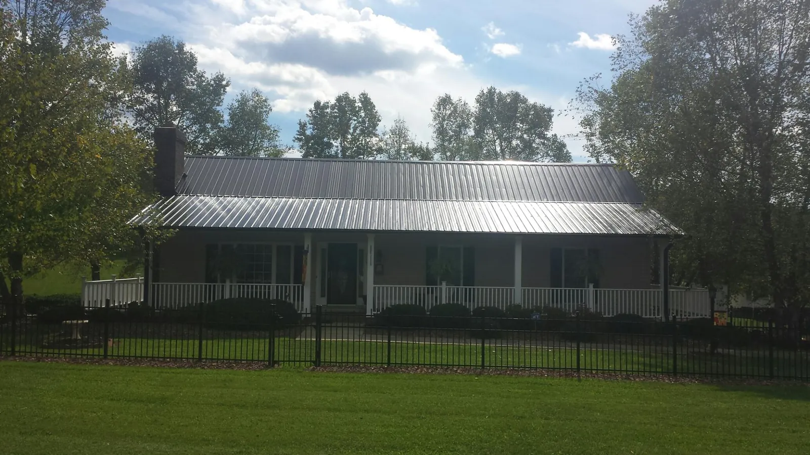 Gray metal roof on a brick ranch with a full width front porch — Gutter Guard Installation work by our crew in Big Sandy