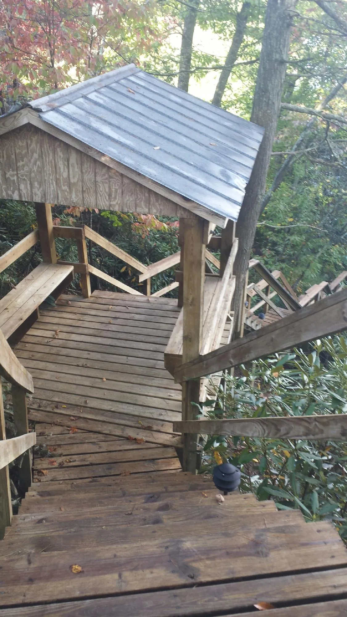 Metal roofed shelter over wooden steps on a wooded walkway — Skylight Repair & Installation work by our crew in Big Sandy