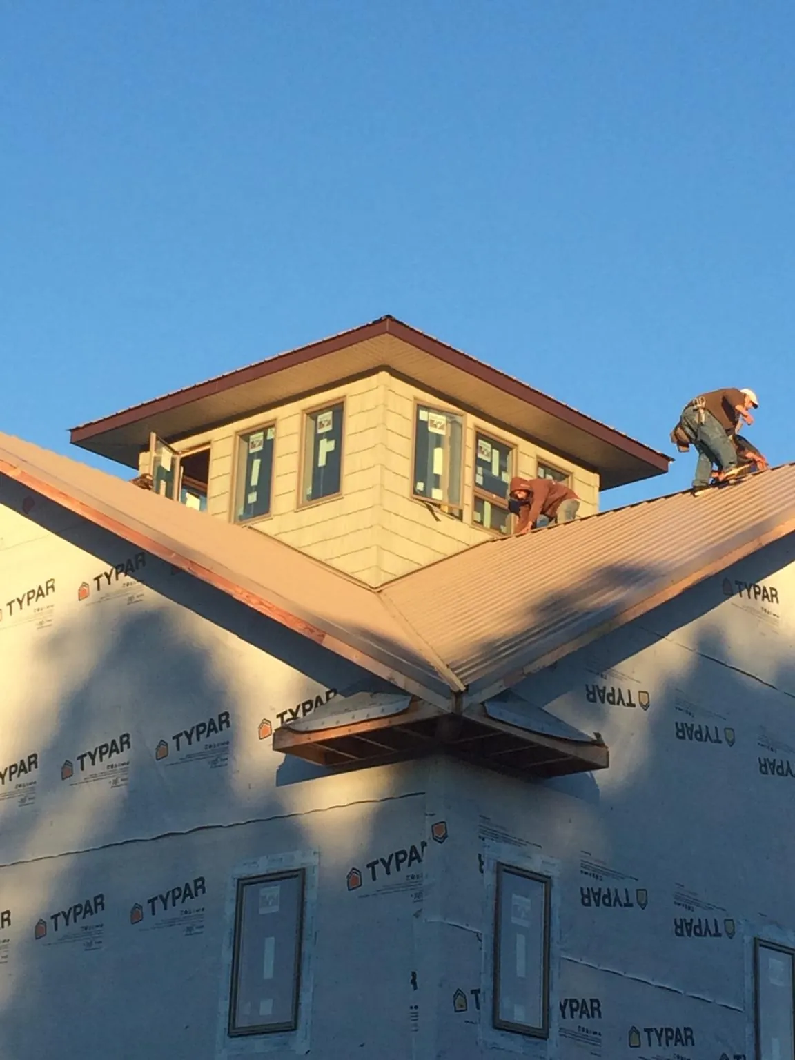 Roofers working around a rooftop cupola on a new metal roof at sunset — Roof Waterproofing in Big Sandy by Roofing Brothers